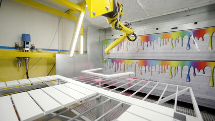 Industrial robotic arm paints frame. Action. Modern equipment for painting furniture in industrial enterprise. Robotic arm paints spray-painted wooden frame in pink