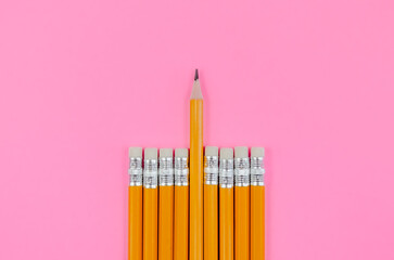 Simple graphite pencils on a pink background. a group of pencils with an eraser, one stands out...
