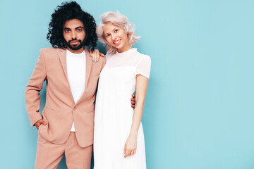 Smiling beautiful woman and her handsome boyfriend. Sexy cheerful multiracial family having tender moments on blue background in studio. Multiethnic models hugging. Embracing each other. Love concept