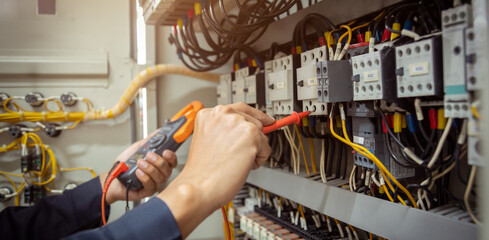 Electrical engineer using measuring equipment to checking electric current voltage at circuit breaker and cable wiring system , Electrical service concept .