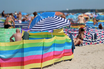 Fototapeta Parasol słoneczny na plaży nadmorskiej w wakacje razem z parawanem na wiatr.
 obraz