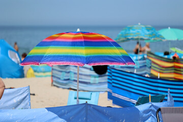 Fototapeta Parasol słoneczny na plaży nadmorskiej w wakacje razem z parawanem na wiatr.
 obraz