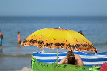 Parasol słoneczny na plaży nadmorskiej w wakacje razem z parawanem na wiatr.
