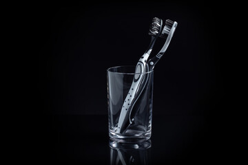 Two toothbrushes in a glass with copy space on black