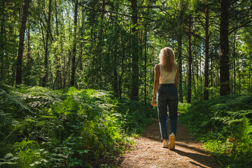 The young woman walks through a dark forest on a sunny day
 - Powered by Adobe