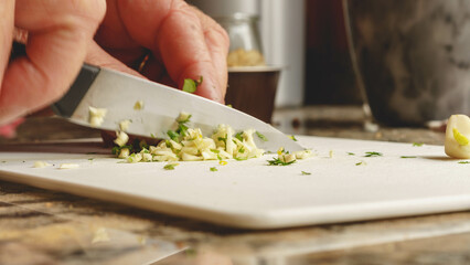 Obraz na płótnie Canvas chop garlic and parsley with a knife