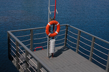 Red life buoy on a wooden boat pier by the sea