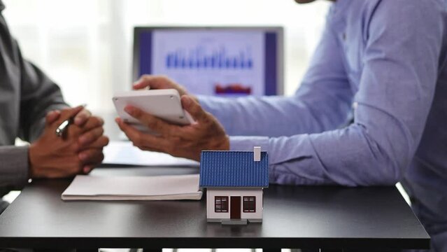 Businessmen discuss real estate project ideas and plan budget allocations to maximize profits. Real estate agents who are talking about homes are offering customers the prices of housing projects.