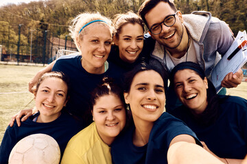 Obraz premium Women's soccer team and their coach taking selfie on playing field.