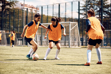 Female soccer players having sports training on playing field.