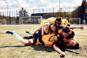 Cheerful female soccer players celebrate after match on playing field.