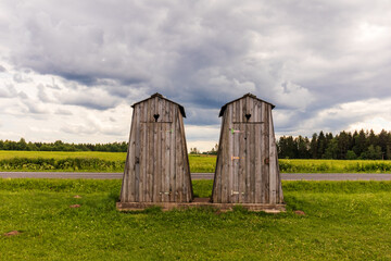 two twin wooden houses on green green grass and dark cloudy sky