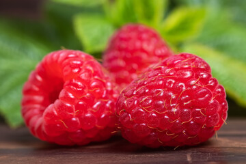 Ripe fresh raspberries with leaves on a wooden background