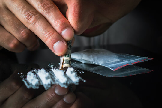 Man hands rolls banknote for using cocaine powder lines. Drug addiction concept. Concept of addiction.