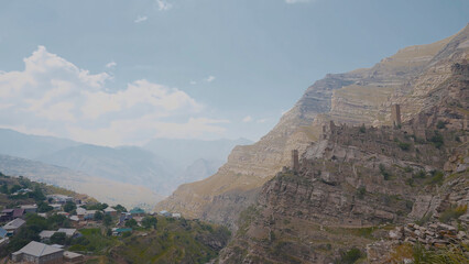 Obraz premium Village near cliff with ruins. Action. Top view of stone city in mountains above residential village. Ancient stone ghost town in mountains
