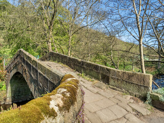 Old stone bridge in Hebden Bridge, West Yorkshire, in early spring, crossing Hebden Beck at the end...