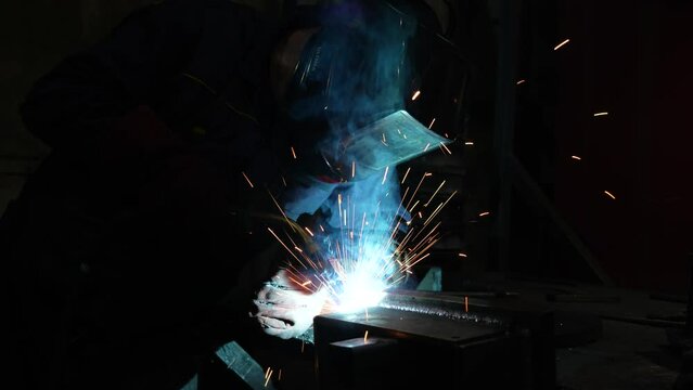 Welder at work close-up, bright sparks in the dark