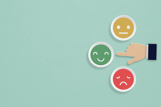 customer feedback, rating, evaluation, vote concept. businessman hand point at happy face on paper cut with grunge green background including copy space