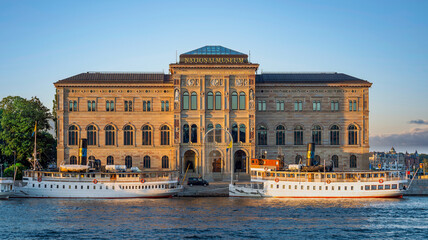 Fototapeta premium Nationalmuseum, or National Museum of Fine Arts, located on the peninsula Blasieholmen in central Stockholm, Sweden - View from Stockholms stromo with ferries parked in front at sunset in a summer day