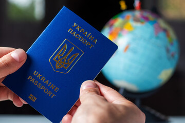 Ukraine, passporton the background of the globe. Ukrainian passports in hands are on the world map....