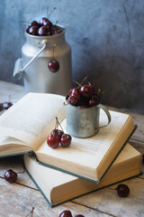 Cherry with water drops from the leaves on a wooden box on a dark brown stone table. Ripe, ripe cherries. Sweet red cherries in a cup and jar. View from above. Country style. Fruit background.
