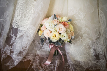 A bright bouquet stands on a wedding dress