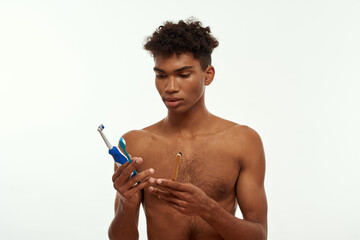 Focused black guy choose and look at toothbrushes