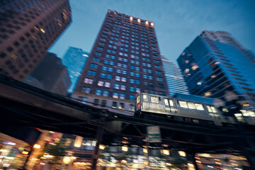 Elevated train in Chicago in blurred motion against skyscrapers in downtown disctrict at night..