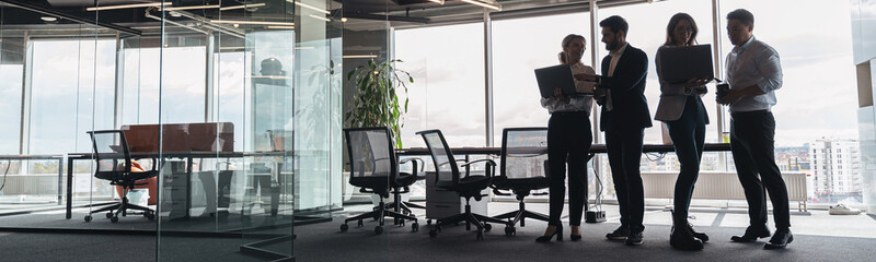 People standing near table, team of businessmen working and communicating together in modern office