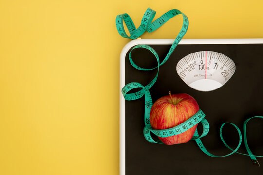 Weight scale and a measure tape with fresh apple , Healthy diet for weight loss control concept