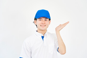 右側を掌で指すキャップとポロシャツのユニフォームの男性