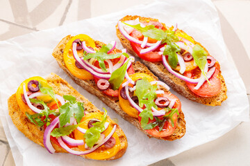 Healthy vegetarian toasts on parchment paper. Vegetarian sandwiches with fresh tomato, greens and olives. Vegetarian spanish tapas on til. Top view