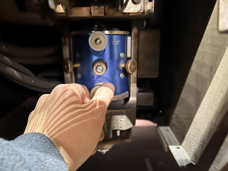 close-up of the hand of an unrecognizable person adjusting and adjusting the lens to make a precise cut on a CNC laser cutting machine in a metallurgical industry.