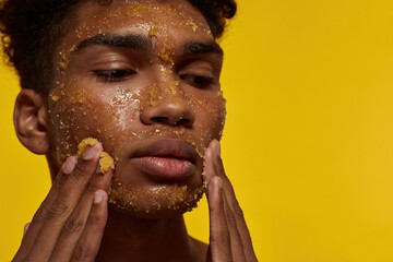Cropped of guy touching his face with honey scrub