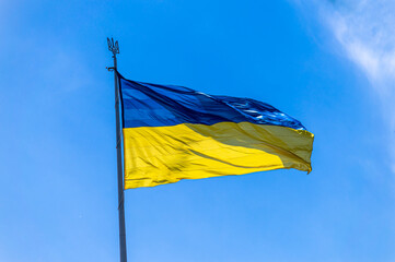 The national flag of Ukraine flies on wind in the blue sky