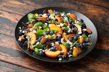 Peach, blueberry salad with vegetables, feta cheese and pecan nuts. Healthy summer food