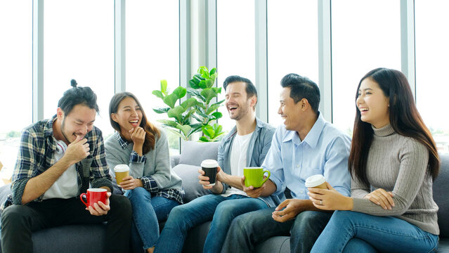 Group of happy creative team talking while taking coffee break at office