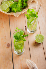 Mojito cocktail and ingredients on wooden boards. Two glasses of mojito with mint and lime. Summer drink with bamboo straw