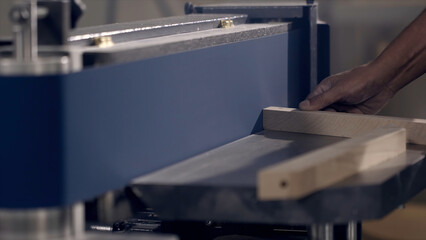 Close-up of man grinds wood products on industrial machine. Action. Carpenter polishes wooden...