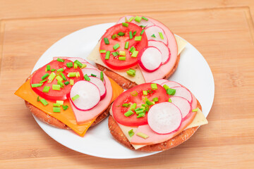 Crispy Cracker Sandwiches with Tomato, Sausage, Cheese, Green Onions and Radish on White Plate. Easy Breakfast. Quick and Healthy Sandwiches. Crispbread with Tasty Filling. Healthy Dietary Snack