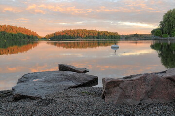 Nice cliffs at a lake. Evening during the summer. Reflection in the calm water Forest and trees in the background. Stockholm, Sweden, Scandinavia, Europe.