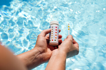 Checking the water quality of a pool with the help of a test strip with PH value, chlorine and...