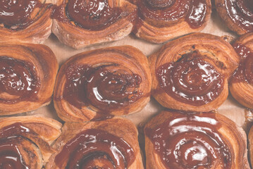 Homemade cinnamon buns with spices and caramel on parchment paper.