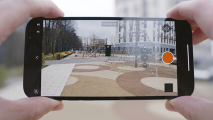 Close-up of screen of phone taking video. Action. Man holds phone and takes video of playground and...