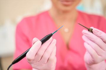 Woman beautician holds radio wave scalpel in her hands