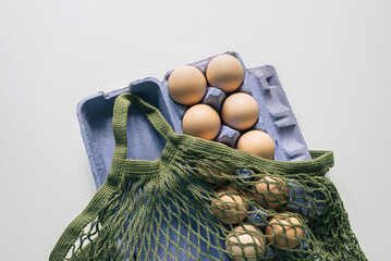 Mesh reused shopping bag with eggs on white background.