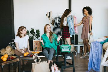 four young woman female caucasian and african students at swap party try on clothes, bags, shoes...