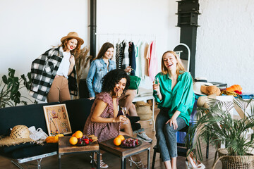 four young woman female caucasian and african students at swap party try on clothes, bags, shoes...