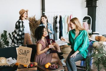 four young woman female caucasian and african students at swap party try on clothes, bags, shoes...