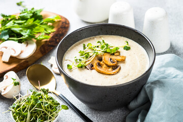 Mushroom Soup in black bowl on light stone table.